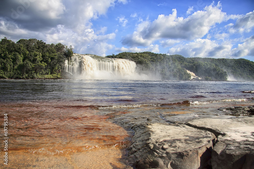 Beautiful powerful waterfall flowing into the lake photo