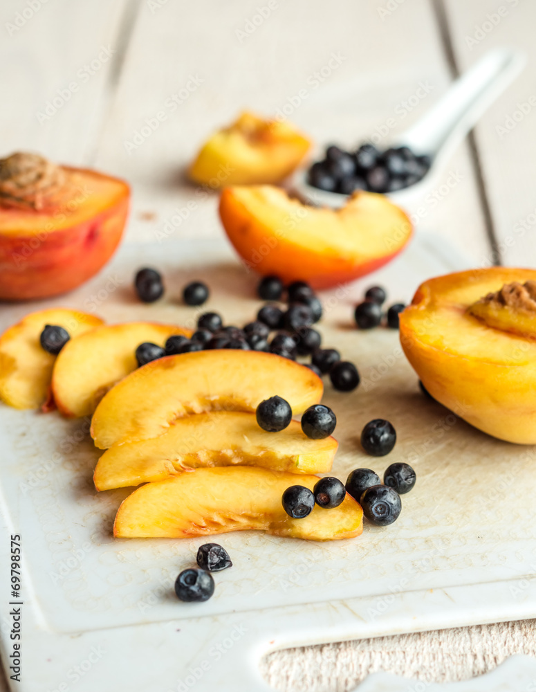 Slices of juicy peaches and blueberries on a white board Slices of juicy peaches and blueberries on a white board