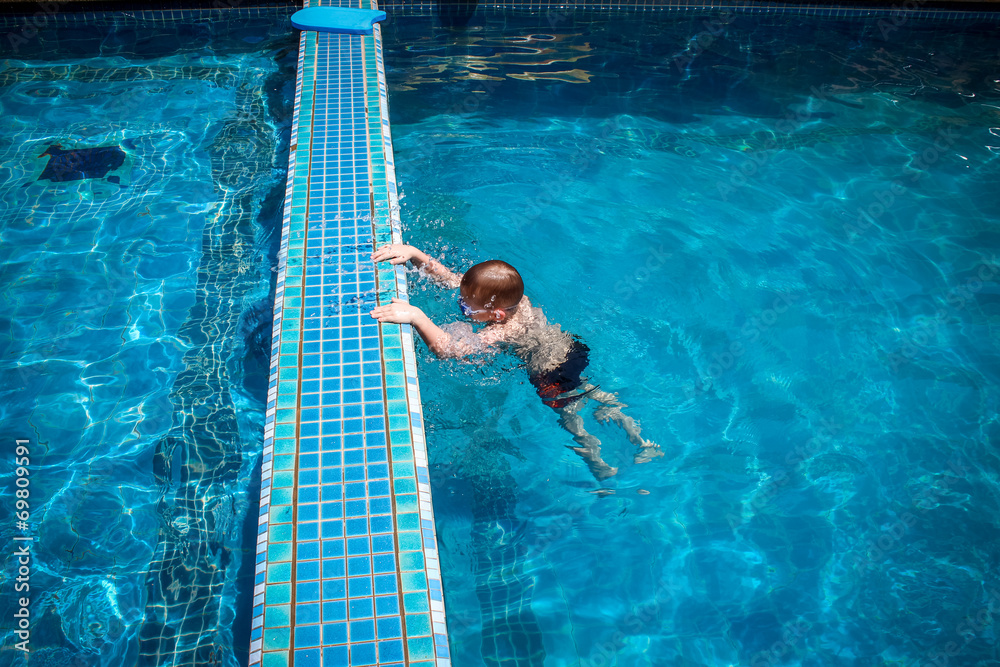 boy swims into blue swimming pool in resort. Koh Samui