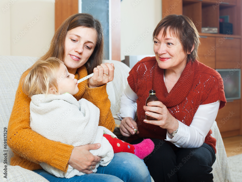  woman with mature mother giving medicinal sirup to toddler