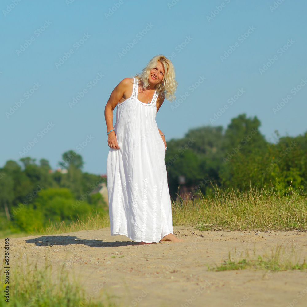 Mature beautiful blonde walks on the sandy road Mature beautiful blonde walks on the sandy road