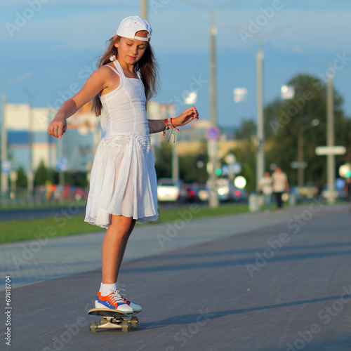 teenage girl riding a skateboard on the evening street