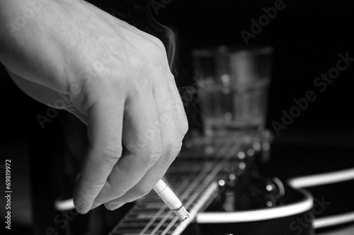 Composition of guitar and man's hand with cigarette smoking