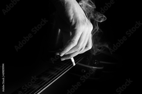 Composition of guitar and man's hand with cigarette smoking