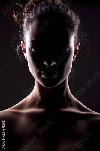 portrait of a woman with the face in shadow on a dark background