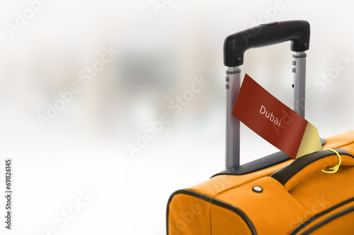 Photography Dubai. Orange suitcase with label at airport.