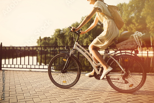Girl riding a bicycle in park near the lake. Lightleak effect an