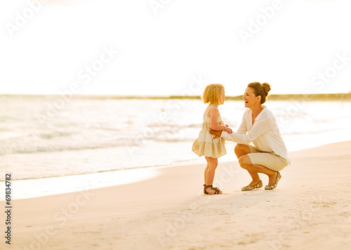 Mother and baby girl playing on the beach in the evening