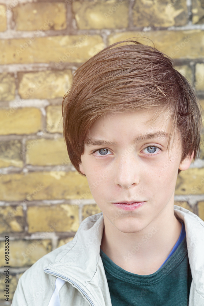portrait of a teenager boy in front of a brick wall portrait of a teenager boy in front of a brick wall