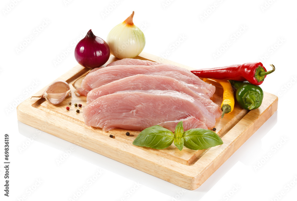 Raw turkey fillets on cutting board and vegetables Raw turkey fillets on cutting board and vegetables