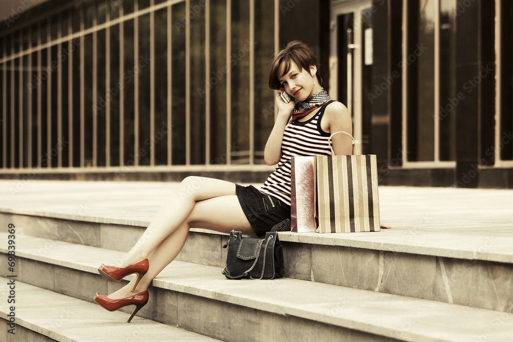 Young fashion woman with shopping bags calling on the phone Young fashion woman with shopping bags calling on the phone