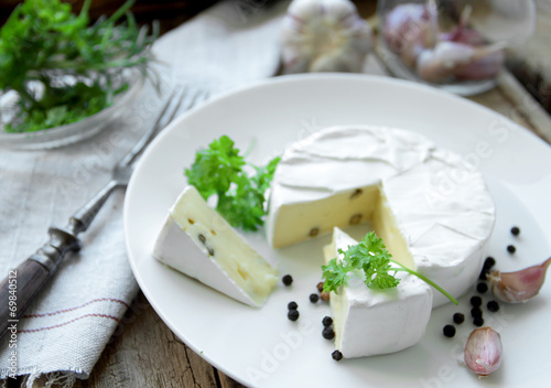 Camembert cheese with herbs on a white plate for appetizer