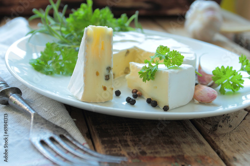 Plate with french camembert cheese with fresh herbs and spices