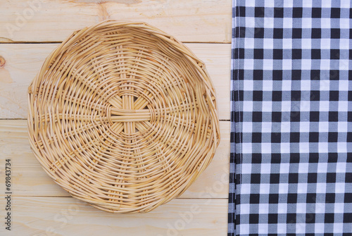 Rattan plate or basket on wooden table and tablecloth on table w