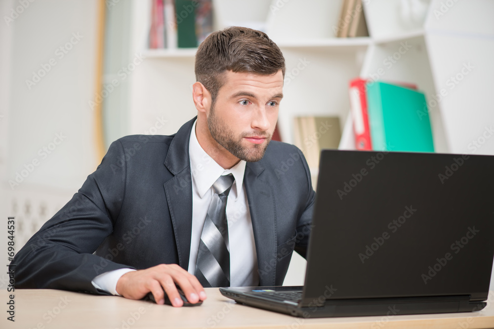 Businessman sitting at the table and working with laptop in offi Businessman sitting at the table and working with laptop in offi