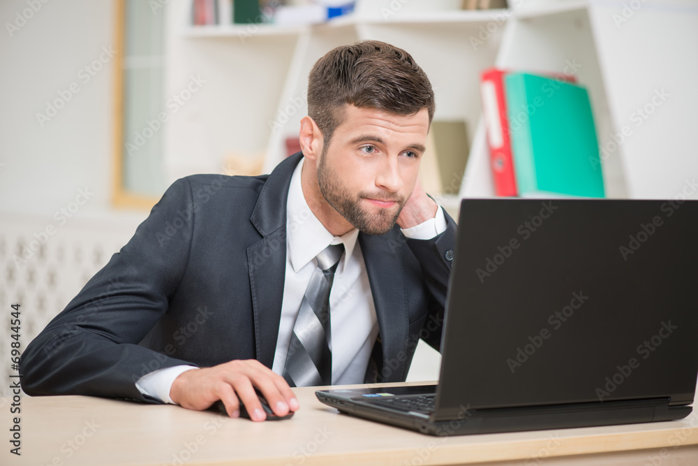 Businessman sitting at the table and working with laptop in offi Businessman sitting at the table and working with laptop in offi