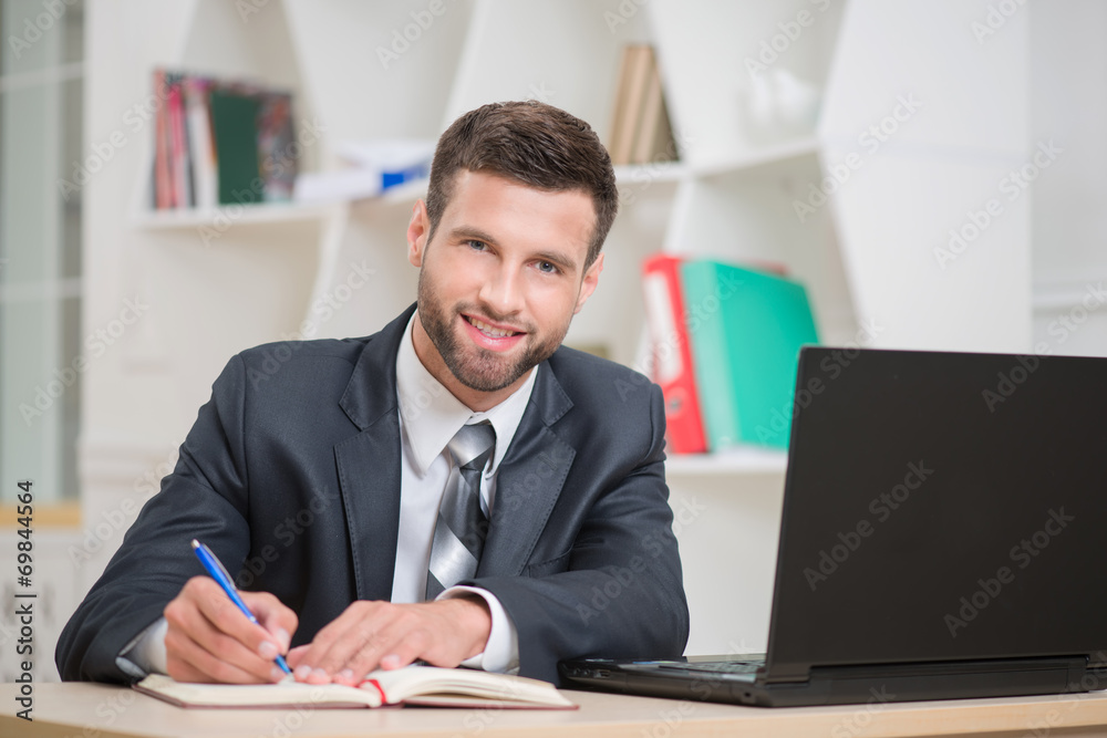 Portrait of handsome confident businessman writing in red notebo Portrait of handsome confident businessman writing in red notebo