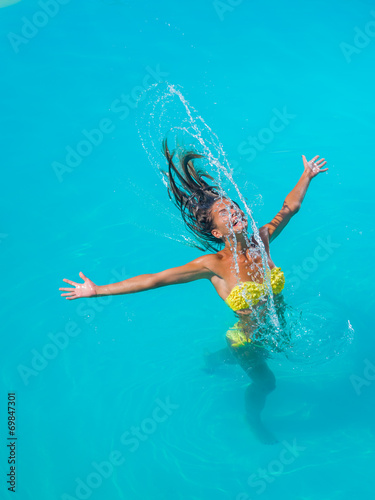 young tanned girl throwing wet hair back in swimming pool