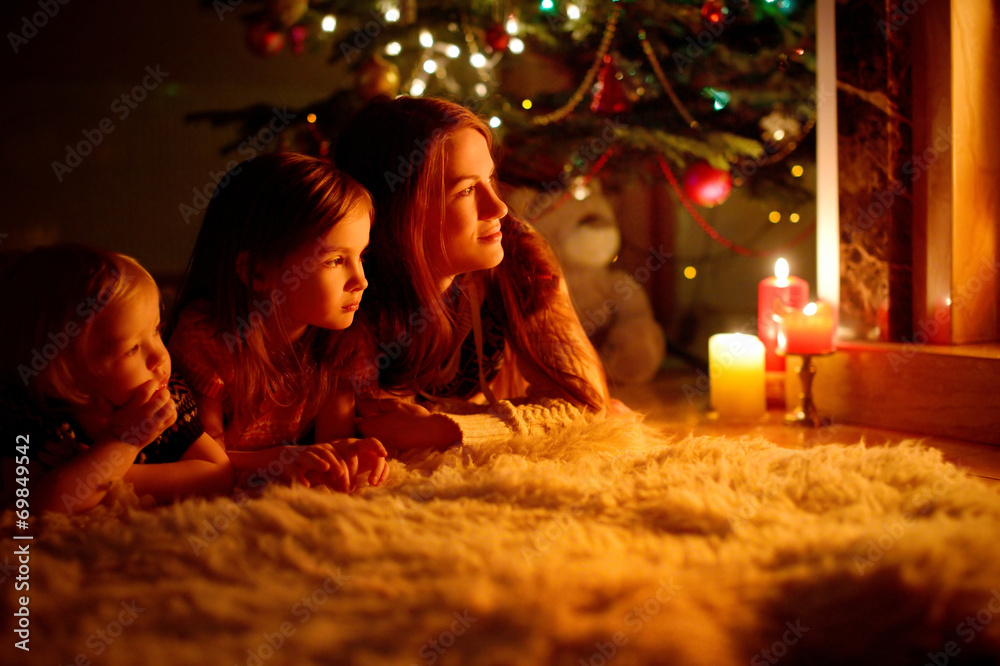 Happy family by a fireplace on Christmas - obrazy, fototapety, plakaty 