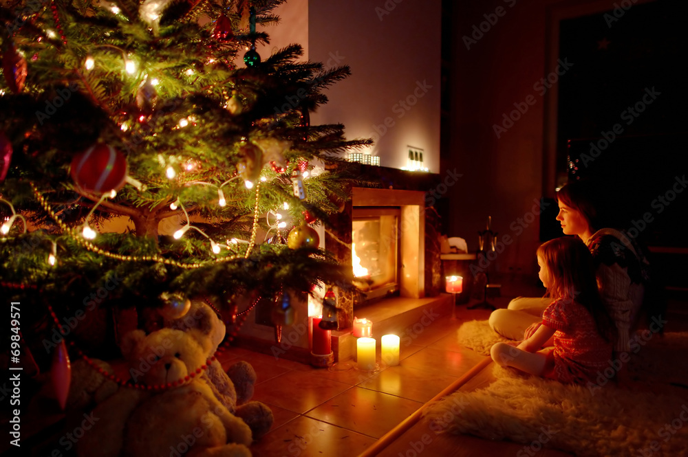 Young mother and her daughter by a fireplace Young mother and her daughter by a fireplace