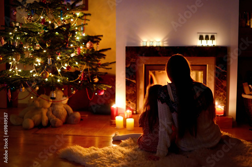 Young mother and her daughter by a fireplace