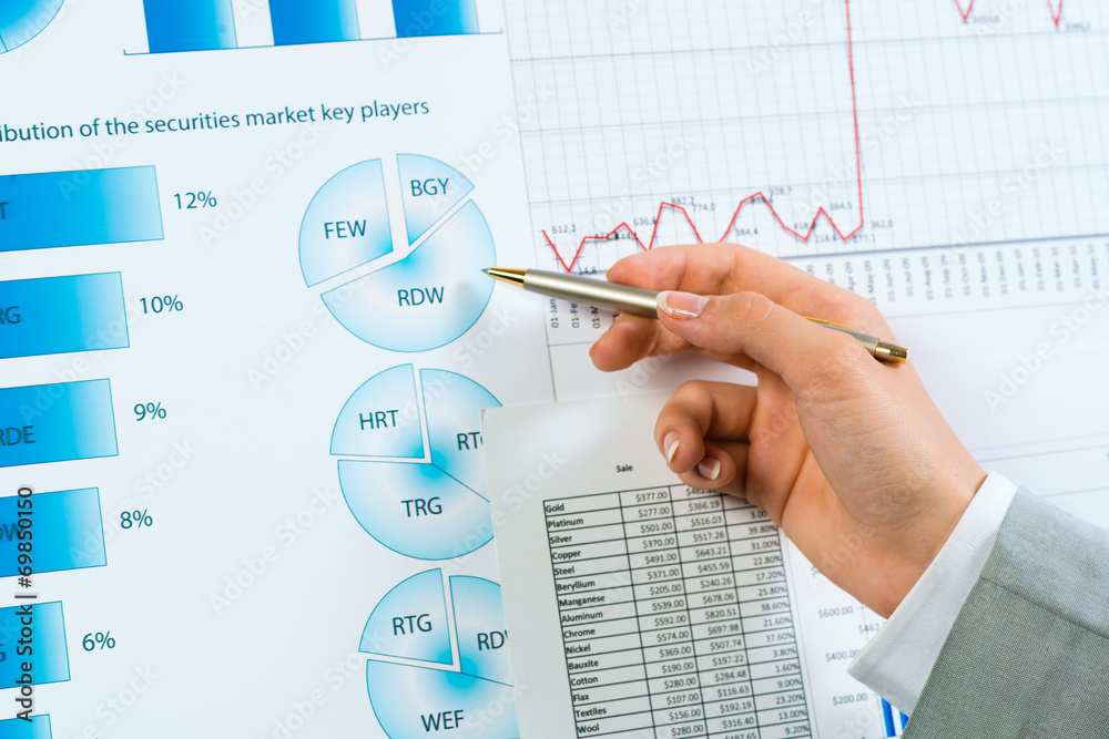 female hand pointing pen on financial charts female hand pointing pen on financial charts