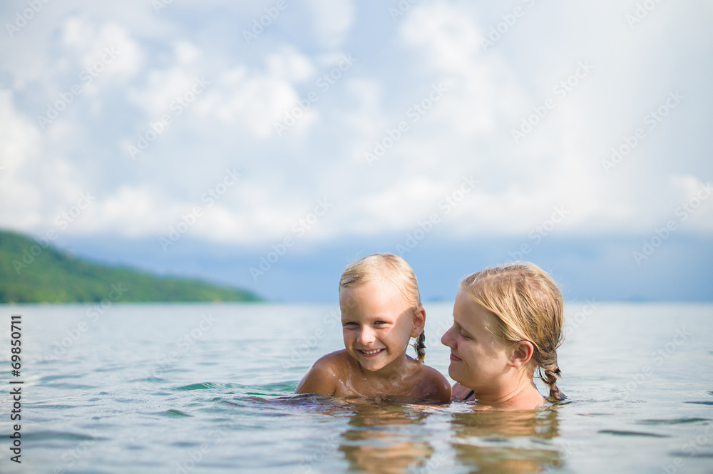 Young mother and daughter have fun swim on island in tropical oc Young mother and daughter have fun swim on island in tropical oc
