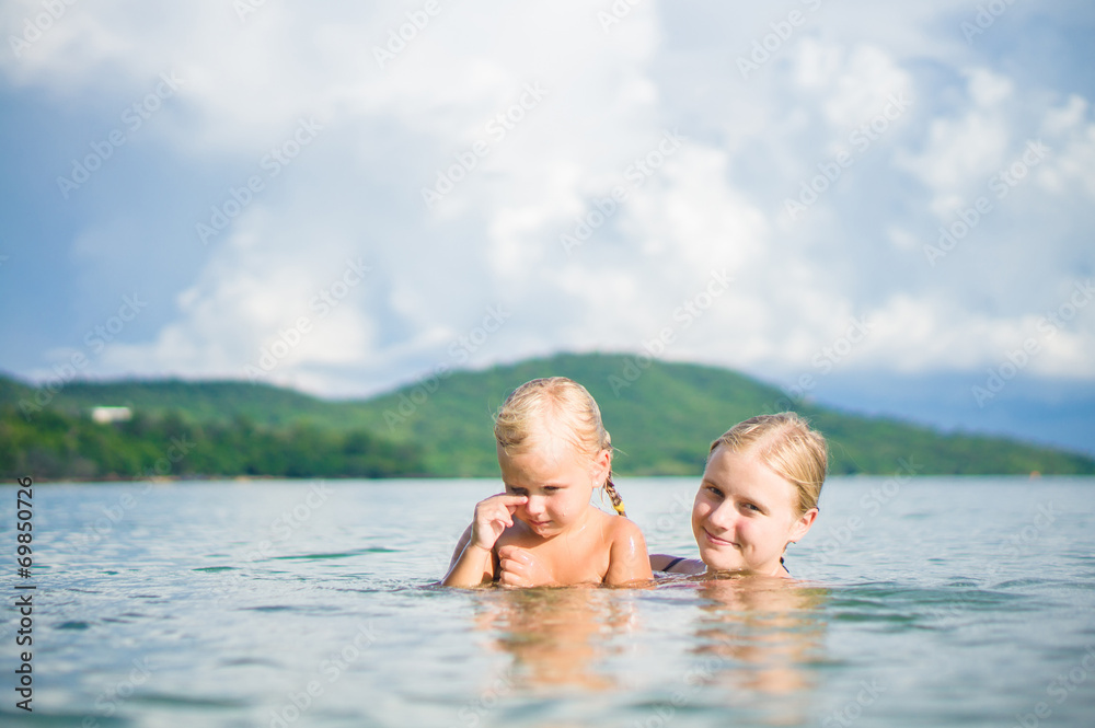Young mother and daughter have fun swim on island in tropical oc Young mother and daughter have fun swim on island in tropical oc
