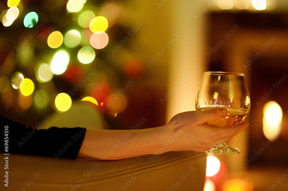 Woman with a drink by a fireplace on Christmas Woman with a drink by a fireplace on Christmas