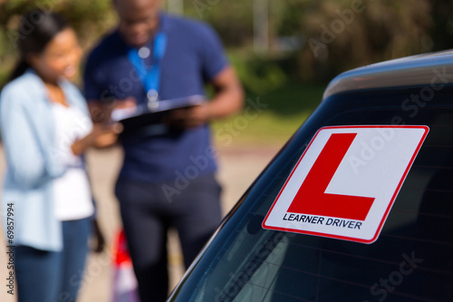 Foto learner driver and instructor behind a car
