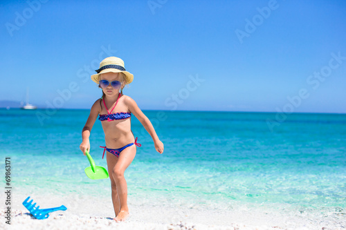 Adorable little girl playing with toy on beach vacation