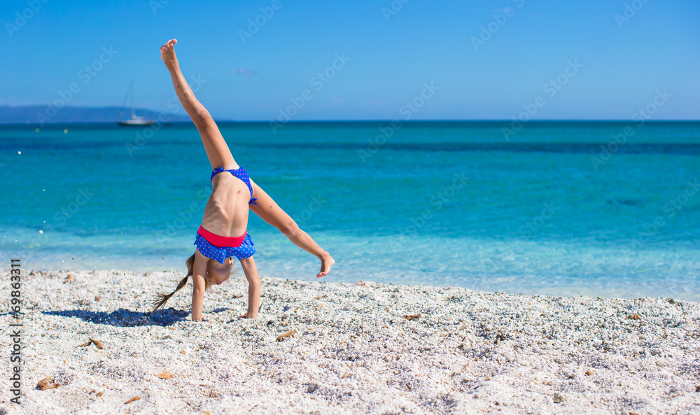 Adorable little girl making wheel on tropical white sandy beach Adorable little girl making wheel on tropical white sandy beach