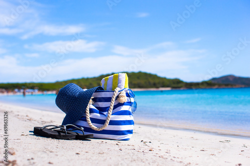 Straw hat, bag, sunglasses and towel on white tropical beach