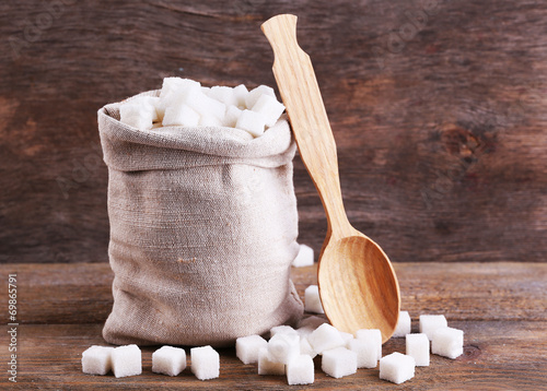 Refined sugar in bag on wooden background