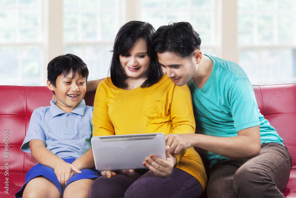 Obraz premium Happy family using digital tablet on couch