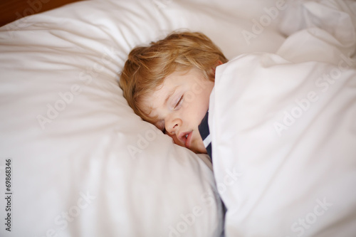 Little blond boy sleeping in his bed