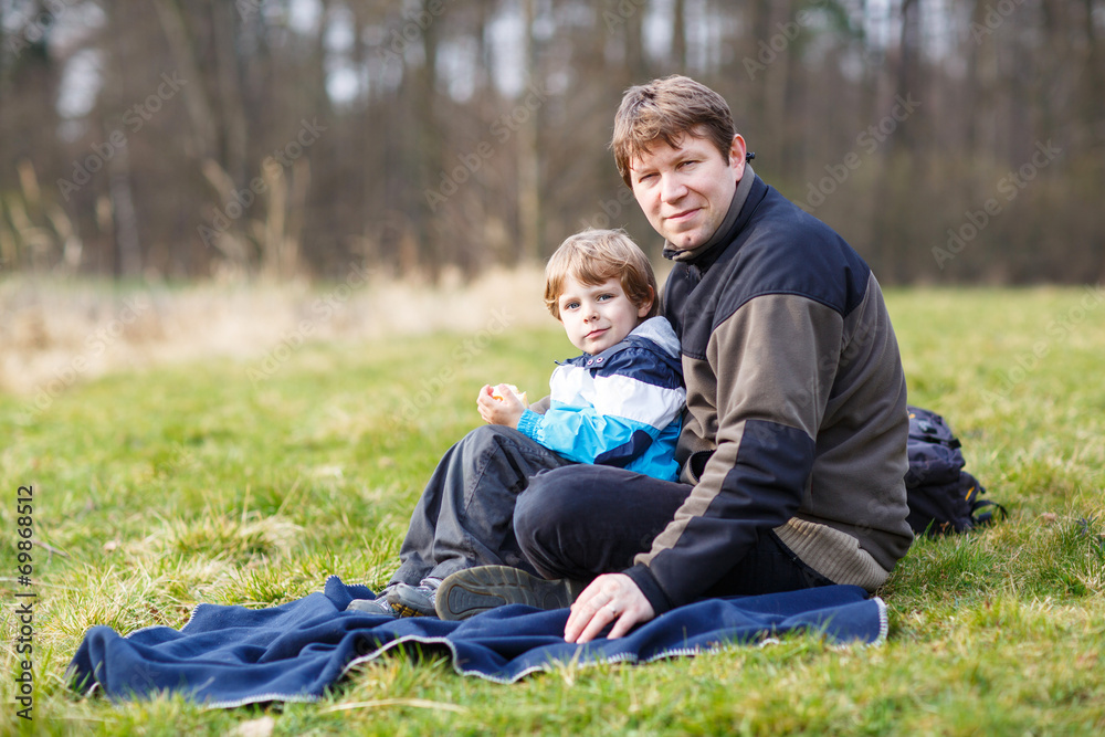 Young father and little son having picnic and fun near forest la Young father and little son having picnic and fun near forest la