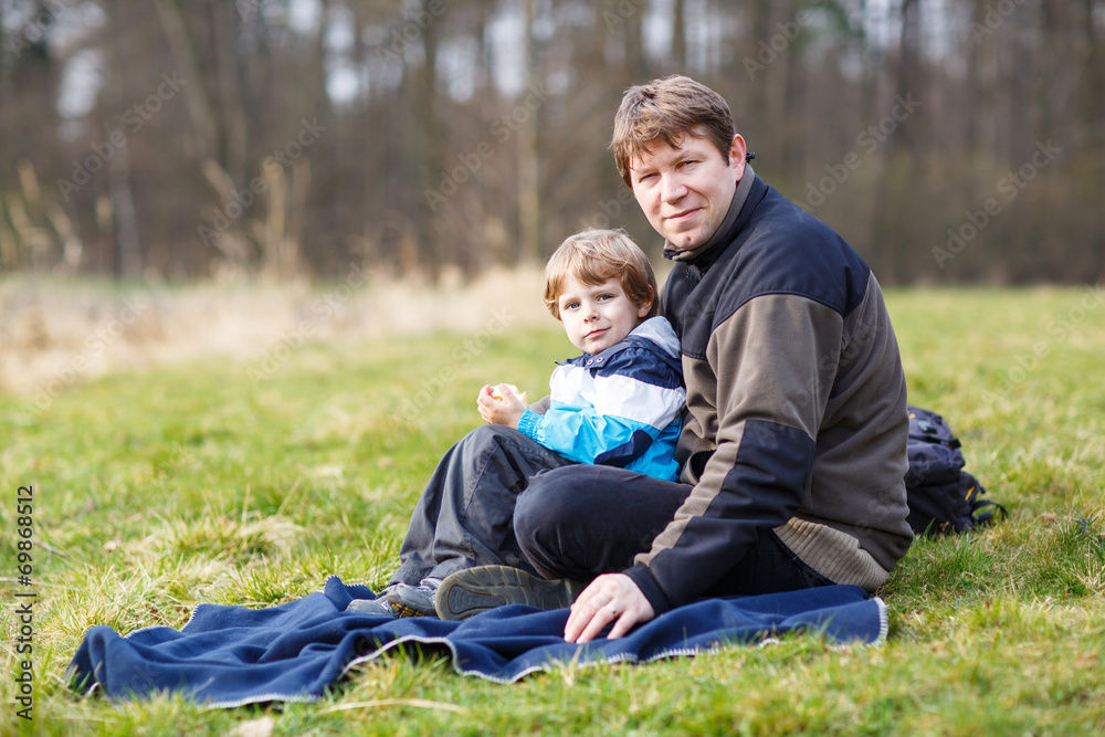 Young father and little son having picnic and fun near forest la