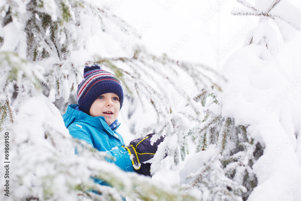 Little toddler boy having fun with snow outdoors on beautiful wi