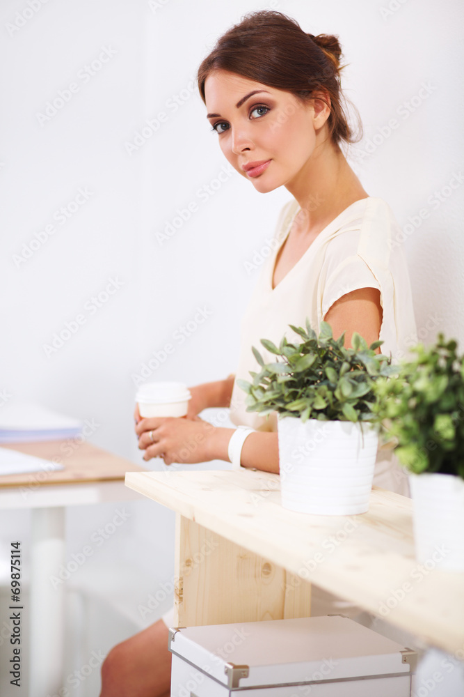 Attractive young businesswoman standing near desk in the office Attractive young businesswoman standing near desk in the office