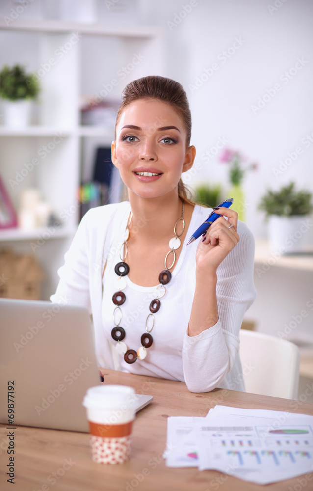 Young businesswoman sitting on the desk with cup in office Young businesswoman sitting on the desk with cup in office