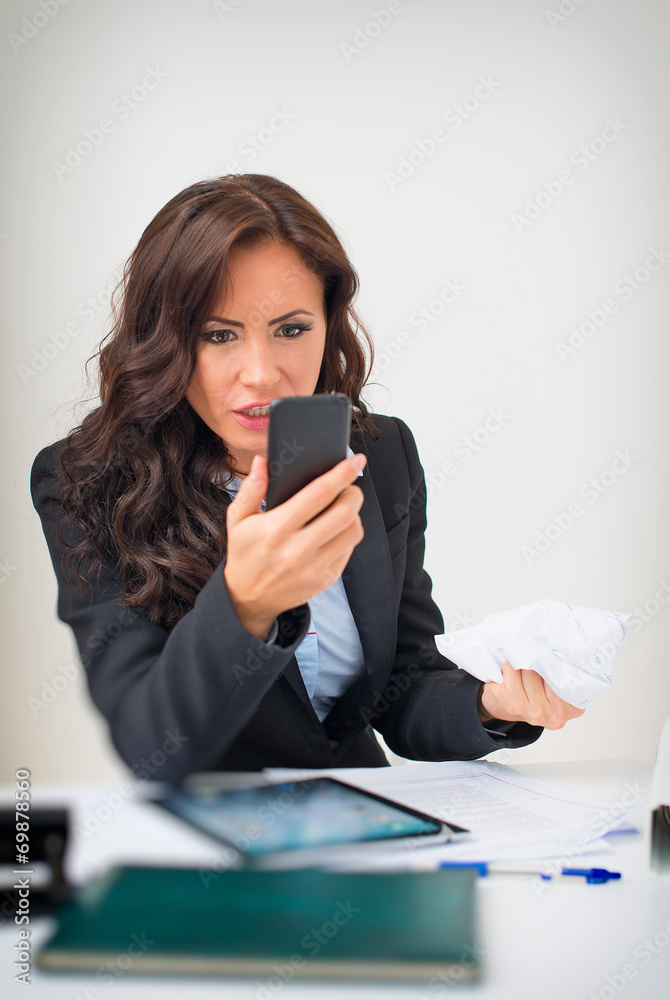 Angry businesswoman with phone in office. Angry businesswoman with phone in office.