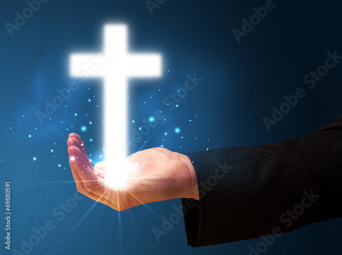 Glowing cross in the hand of a businessman