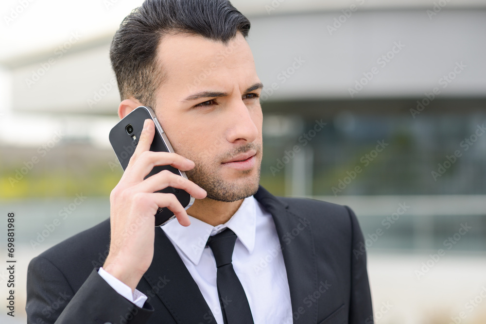 Attractive young businessman on the phone in an office building Attractive young businessman on the phone in an office building