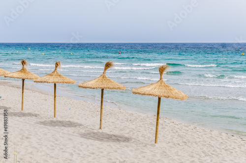 Straw umbrellas on sand beach.