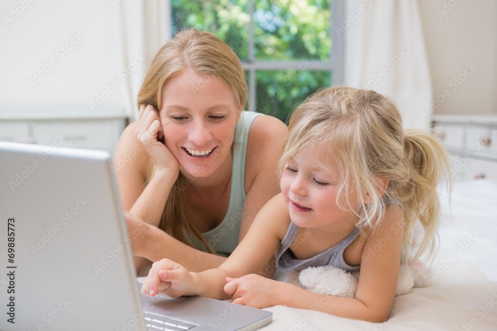 Cute little girl and mother on bed using laptop Cute little girl and mother on bed using laptop