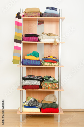 Wardrobe with winter clothes nicely arranged on a shelf.