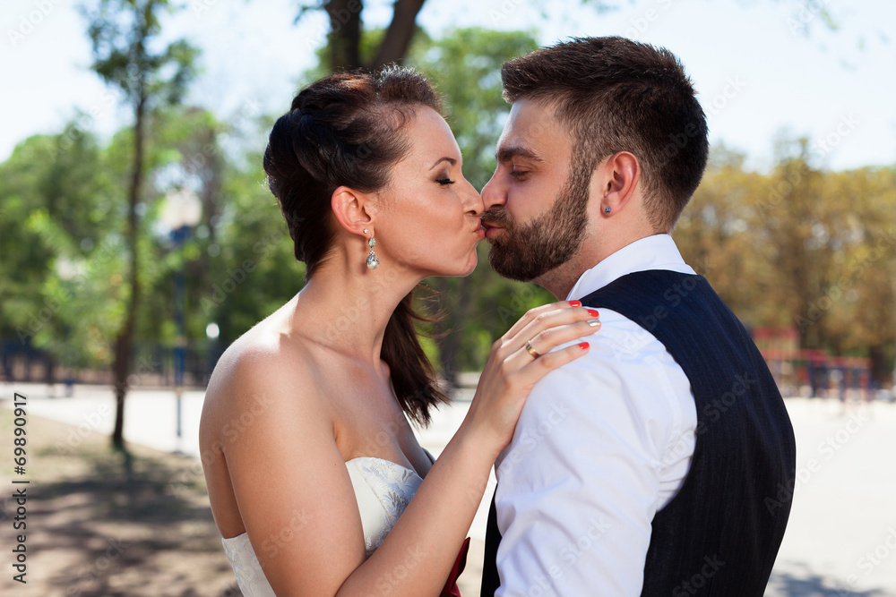 European bride and groom kissing in the park European bride and groom kissing in the park
