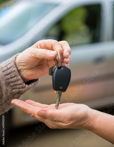 Woman giving keys from a car to another woman