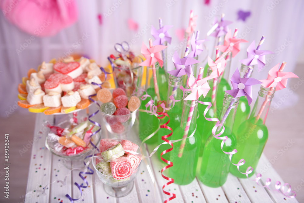 Bottles of drink with straw and sweets on decorative background Bottles of drink with straw and sweets on decorative background